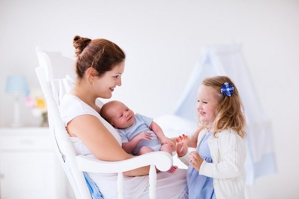 Mother with daughter and baby in a white nursery